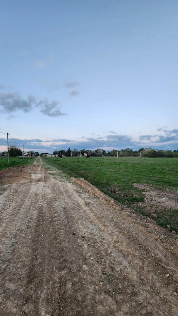 Acceso al loteo Altos de Lavalle, calle de tierra con verde a los costados